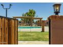 View of a community pool featuring a metal fence, pergola, and grassy area at 6008 W Augusta Ave, Glendale, AZ 85301