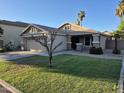 Well-manicured lawn complements this desert home with a two-car garage and trimmed landscaping at 7027 W Midway Ave, Glendale, AZ 85303