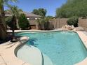 Inviting in-ground pool featuring a small rock waterfall, lush landscaping, and a pristine patio at 9018 W Superior Ave, Tolleson, AZ 85353
