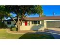 Charming exterior of a single story home, featuring a well-manicured lawn, mature trees, and a bright red door at 3109 E Cholla St, Phoenix, AZ 85028