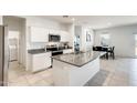 Bright kitchen features white cabinets, stainless appliances, granite countertops and an island with sink at 35816 W San Ildefanso Ave, Maricopa, AZ 85138