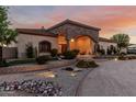 Stunning exterior view featuring a stone facade, arched entryway, and professionally landscaped front yard at 3718 N Briere Ct, Buckeye, AZ 85396