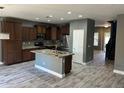Open kitchen with a granite island, stainless steel appliances, wood cabinetry, and gray walls at 38242 N Armadillo Dr, San Tan Valley, AZ 85140
