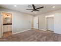 Spacious bedroom with carpet, a ceiling fan, and access to the ensuite bathroom and closets at 4001 E Apollo Rd, Phoenix, AZ 85042