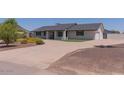 Single story home with white painted brick, a dark roof and mature landscaping on a sunny day at 5102 W Whispering Wind Dr, Glendale, AZ 85310