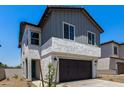 Two-story home featuring grey siding, stucco base, dark garage door, minimal desert landscaping, and a green door at 9408 E Sequence Ave, Mesa, AZ 85212