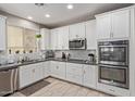 Modern kitchen features white cabinets, stainless steel appliances, mosaic backsplash, and ample counter space at 9412 S 34Th Dr, Laveen, AZ 85339