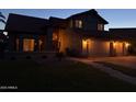 Attractive two story home with tile roof, three-car garage, and green lawn at twilight at 1010 N Osprey Ct, Gilbert, AZ 85234