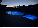 Backyard pool and spa illuminated with blue lights at night at 1010 N Osprey Ct, Gilbert, AZ 85234