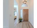 Bright entryway featuring a wooden front door, high ceilings, decorative lighting, and views into the living area at 17293 N Ponca Way, Surprise, AZ 85374
