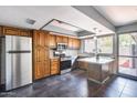 Kitchen featuring wood cabinets, granite countertops, stainless steel appliances, and view to the backyard at 1822 W Marlette Ave, Phoenix, AZ 85015