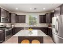 Modern kitchen boasts dark cabinetry, granite countertops, stainless steel appliances, and a center island at 20565 W Terrace Ln, Buckeye, AZ 85396