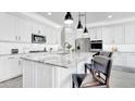 Bright white kitchen features an island with granite countertops and modern pendant lighting overhead at 22515 E Sonoqui Blvd, Queen Creek, AZ 85142
