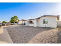 Street view of single-story home with white exterior, rock landscaping, and covered parking at 2508 N 58Th Ln, Phoenix, AZ 85035