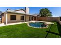 Backyard view featuring a kidney-shaped pool, artificial grass and covered patio at 8668 N 107Th Dr, Peoria, AZ 85345