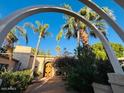 Stunning Mediterranean home entrance with archway, tropical palms, and custom double doors at 94 Biltmore Estates Dr, Phoenix, AZ 85016