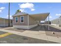 Tan single Gathering home displaying a carport in a neighborhood of similar homes with blue skies overhead at 320 E Mckellips Rd # 245, Mesa, AZ 85201