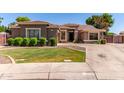 Landscaped front yard featuring green lawn, manicured shrubbery, and a concrete driveway leading to the garage at 557 S Lemon Ct, Gilbert, AZ 85296