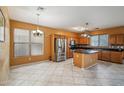Open kitchen with stainless steel appliances, center island with granite countertops and tile floors at 9912 W Illini St, Tolleson, AZ 85353