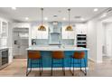 Modern kitchen with stainless steel appliances, stylish island, white cabinets, and pendant lighting at 129 E Los Andes Ln, Queen Creek, AZ 85140