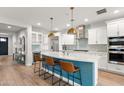 Open kitchen with a large center island, stainless appliances, modern lighting and hardwood floors at 129 E Los Andes Ln, Queen Creek, AZ 85140