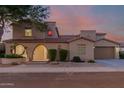Twilight view of a two-story home featuring an arched entryway, well manicured yard, and a two-car garage at 16178 W Granada Rd, Goodyear, AZ 85395
