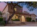Twilight view of a two-story home featuring mature landscaping, terracotta roof, and a gated entryway at 16178 W Granada Rd, Goodyear, AZ 85395