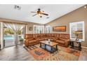 Spacious living room featuring a large leather sectional, wood-look floors, shutters, and a sliding door to the pool at 38771 N Dena Dr, San Tan Valley, AZ 85140