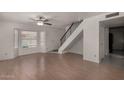 Bright living room featuring a ceiling fan, window with blinds, and staircase at 4644 W Havasupai Dr, Glendale, AZ 85308