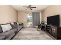 Cozy living room featuring a comfortable gray sofa, sliding glass doors, and a ceiling fan at 5654 W Vineyard Rd, Laveen, AZ 85339