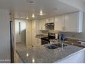 Bright kitchen featuring ample white cabinetry, granite countertops, and stainless steel appliances at 6407 W Madras Ln, Glendale, AZ 85306