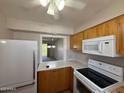 Bright kitchen featuring wood cabinets, white appliances and countertop with breakfast bar at 131 N Higley Rd # 215, Mesa, AZ 85205