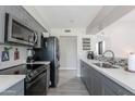 Modern kitchen featuring gray cabinets, stainless appliances, and light countertops, backsplash, and grey flooring at 17634 N 34Th Ln, Phoenix, AZ 85053