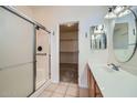 Well-lit bathroom features a tiled shower with glass door, single vanity, and access to walk-in closet at 2729 N Kenton St, Mesa, AZ 85215
