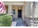 Charming front entrance showcasing stone accents, a covered porch, and a stylish black front door at 3058 E Spring Wheat Ln, Gilbert, AZ 85296