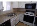 Kitchen with white cabinets, tan countertops, and black and stainless appliances at 413 E Bruce Ave # D, Gilbert, AZ 85234