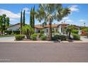 Beautiful front exterior featuring lush landscaping, desert plants, and a circular driveway at 5320 W Soft Wind Dr, Glendale, AZ 85310