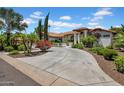 Expansive circular driveway leads to a beautifully landscaped home with desert plants and mature trees at 5320 W Soft Wind Dr, Glendale, AZ 85310