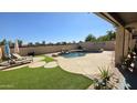 Inviting backyard pool featuring a rock waterfall, lush landscaping, and lounge chairs for relaxation at 1075 E Crimm Rd, San Tan Valley, AZ 85143