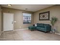 Cozy living room featuring tile flooring, ample natural light, and a comfortable green sofa at 11832 W Electra Ln, Sun City, AZ 85373