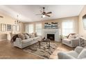 Bright living room with fireplace, wood floors, ceiling fan, and natural light from multiple windows at 15014 N 48Th Pl, Scottsdale, AZ 85254