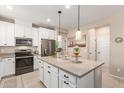 Modern kitchen island with pendant lighting, stainless steel appliances, and white cabinets at 1713 E Bridgeport Pkwy, Gilbert, AZ 85295