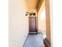 Inviting entryway with brown front door, covered porch, and neutral-toned exterior at 1902 N 106Th Ave, Avondale, AZ 85392