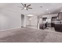 Open-concept living room with plush carpeting and a view into the kitchen and dining area at 28512 N Geode Dr, San Tan Valley, AZ 85143