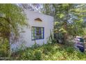 Exterior view showcasing a blue-framed window amidst lush green foliage, providing natural light at 3303 E Clarendon Ave, Phoenix, AZ 85018
