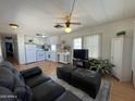 Inviting living room and kitchen area with laminate floors, ceiling fan, and comfortable leather seating at 7807 E Main St # H-20, Mesa, AZ 85207