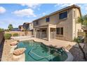 Backyard view showcasing a refreshing swimming pool with a safety fence, surrounded by desert landscaping at 15046 W Post Dr, Surprise, AZ 85374