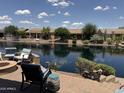 Scenic waterfront backyard featuring brick patio, lush landscaping and comfortable outdoor seating at 20119 N Laguna Way, Maricopa, AZ 85138