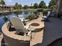 Waterfront backyard with a fire pit and outdoor seating creating a cozy and inviting outdoor space at 20119 N Laguna Way, Maricopa, AZ 85138