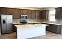 Modern kitchen boasts stainless steel appliances, granite countertops, and dark cabinets with tiled backsplash at 5669 S 253Rd Ave, Buckeye, AZ 85326